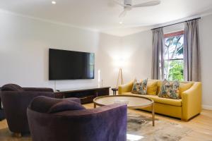 a living room with a yellow couch and a tv at Stony Brook Cottages in Franschhoek