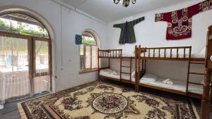 a room with two bunk beds and a rug at Gulzar Village Guesthouse in Dushanbe