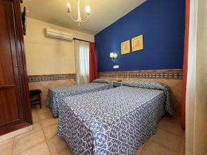 a bedroom with two beds and a blue wall at Pension Doña Trinidad in Seville