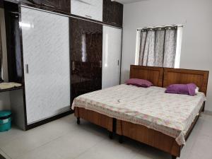 a bedroom with a bed with purple pillows on it at Green fields in Vijayawāda