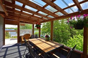 a wooden table and chairs on a porch with a pergola at Sunrise Place Bed & Breakfast in DʼEscousse