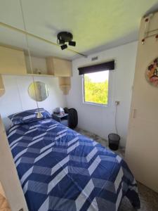 a bedroom with a blue and white bed with a window at Airport Cottage in Aldergrove