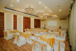 a banquet hall with white tables and white chairs at Hotel Phoenix Koregaon Park in Pune