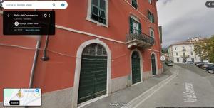 a red building with a green door on a street at La stanzetta in Carrara