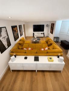 a large yellow couch in a living room at The Old Pub Wiltshire A Unique Luxury Cellar Retreat with Private Sauna Gym and Movie Room in Patney