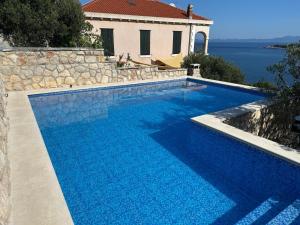 a swimming pool with blue water in front of a house at Vila Mia in Prizba