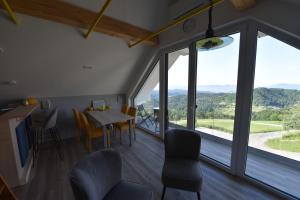 a dining room with a table and chairs and windows at Slovenia Valley Views in Lipa pri Frankolovem +8 photos