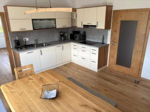 a kitchen with white cabinets and a wooden table at Ferienhaus Meisterl in Sankt Marein bei Neumarkt