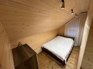 a small bedroom with a bed in a wooden room at Андріана in Mykulychyn