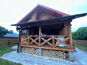 a log cabin with a pile of fire wood at Андріана in Mykulychyn