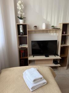 a living room with a television and a bed with towels at Apartment with private entrance in Šilutė