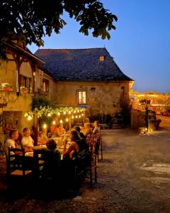 a group of people sitting at tables in front of a building at Gîte authentique avec piscine en Aveyron in Morlhon-le-Haut