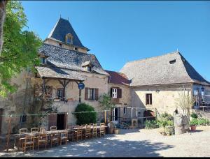 a large building with tables and chairs in front of it at Gîte authentique avec piscine en Aveyron in Morlhon-le-Haut
