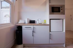 a kitchen with white cabinets and a microwave at Stockton Suites in Stockton-on-Tees