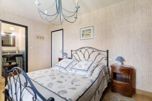 a bedroom with a bed and a chandelier at L'aoûtienne - 300m de la plage in Saint-Coulomb