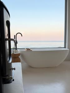 a bathroom with a bath tub and a window at Atlantic Corner in Yzerfontein +29 photos