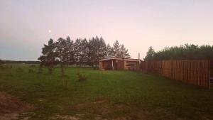 a small house in a field with a fence at Kupolinis namelis Miško Pašvaistėje in Balneliškiai
