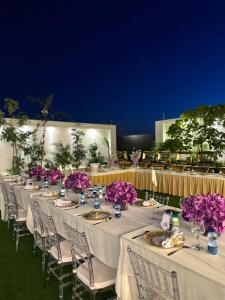 a row of tables with purple flowers on them at شالية هواك in Al Ḩadd