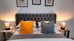 a bed with orange and grey pillows and two lamps at N&K Yellow Pearl Flat in Volos