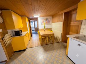 a small kitchen with a table and yellow cabinets at Ferien im Paradies - Zwischen Bergen & Seen in Brienzwiler