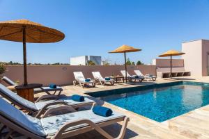 a pool with lounge chairs and umbrellas on a building at Casa Gabriel in Estômbar