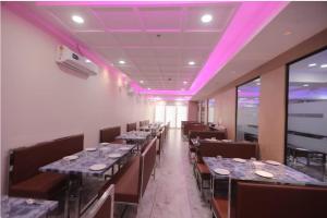 a row of tables in a restaurant with purple lighting at Royal Palace Hotel Surat Velanja in Sāyan