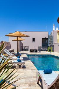 a pool with chairs and umbrellas next to a building at Casa Gabriel in Estômbar
