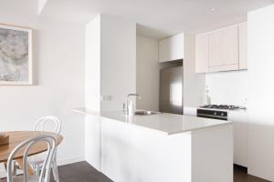 a white kitchen with white cabinets and a table at The Calm in Newcastle