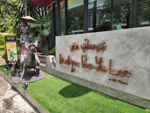 a statue of a monkey riding a donkey next to a sign at Boutique Poo-Yai Lee in Bangkok