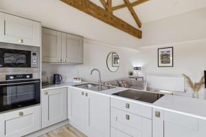 a kitchen with white cabinets and a sink at Heritage Serviced Suites - Serviced Apartments in Huddersfield