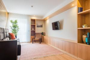 a living room with a couch and a tv on a wall at Almada Domus in Porto