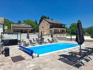 a pool with chairs and umbrellas next to a house at Jakiland house Plitvice Lakes in Korenica