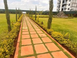 a brick path in a park with trees and a building at Nalim bliss garden in Ruiru