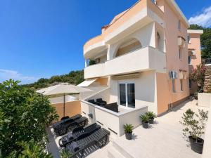 an external view of a house with chairs and an umbrella at Beachside Apartments Novalja in Stara Novalja