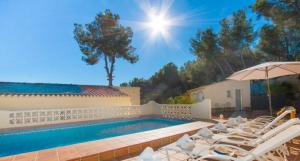 a swimming pool with white chairs and an umbrella at Villa SOFIA - Costa Blanca in Benissa