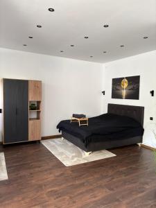 a bedroom with a large black bed and a wooden floor at La Luna Apartman in Bečej