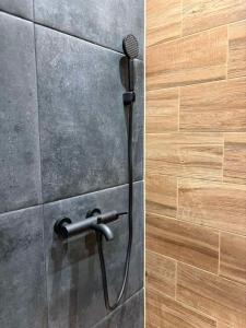 a shower with a microphone on a stone wall at La Luna Apartman in Bečej