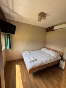 a small bedroom with a bed with white sheets at Wiatrowe Domki in Lądek-Zdrój