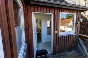 a wooden house with a door and a window at Appartement Tümmelkoje in Sankt Peter-Ording