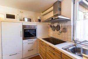 a kitchen with white cabinets and a sink at Appartement Tümmelkoje in Sankt Peter-Ording