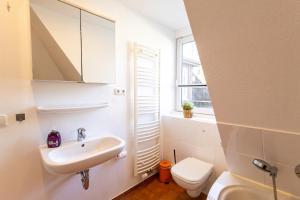 a bathroom with a sink and a toilet and a window at Appartement Tümmelkoje in Sankt Peter-Ording +24 photos