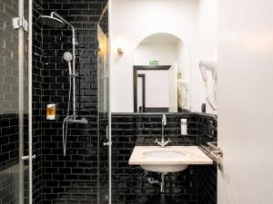 a black tile bathroom with a sink and a shower at The Twenties by GuestReady in Lisbon
