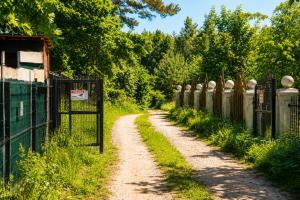a dirt road with a fence next to a field at Domek na Morskiej in Jantar