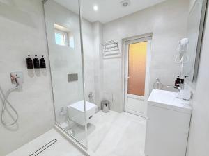 a white bathroom with a shower and a sink at Ismat Premium Guest House in Bukhara