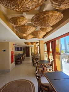 a restaurant with tables and chairs and baskets on the ceiling at Bali Mar Hotel in Natal