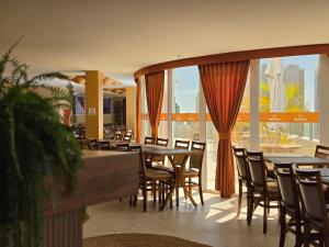 a restaurant with tables and chairs and a large window at Bali Mar Hotel in Natal