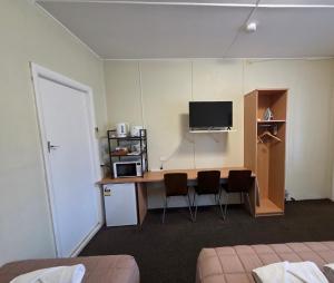 a room with a desk with chairs and a television at Murrurundi Motel - CITY CENTRE in Murrurundi