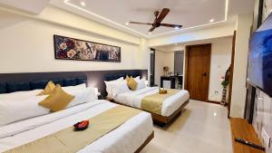 a hotel room with two beds and a flat screen tv at Hotel Aventus Grand in Indore