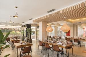 ein Restaurant mit Holztischen und -stühlen und Fenstern in der Unterkunft The Cookbook Hotel & SPA in Calpe