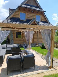 a pergola with couches and chairs in front of a house at Dom goralski Kamilux in Nowy Targ